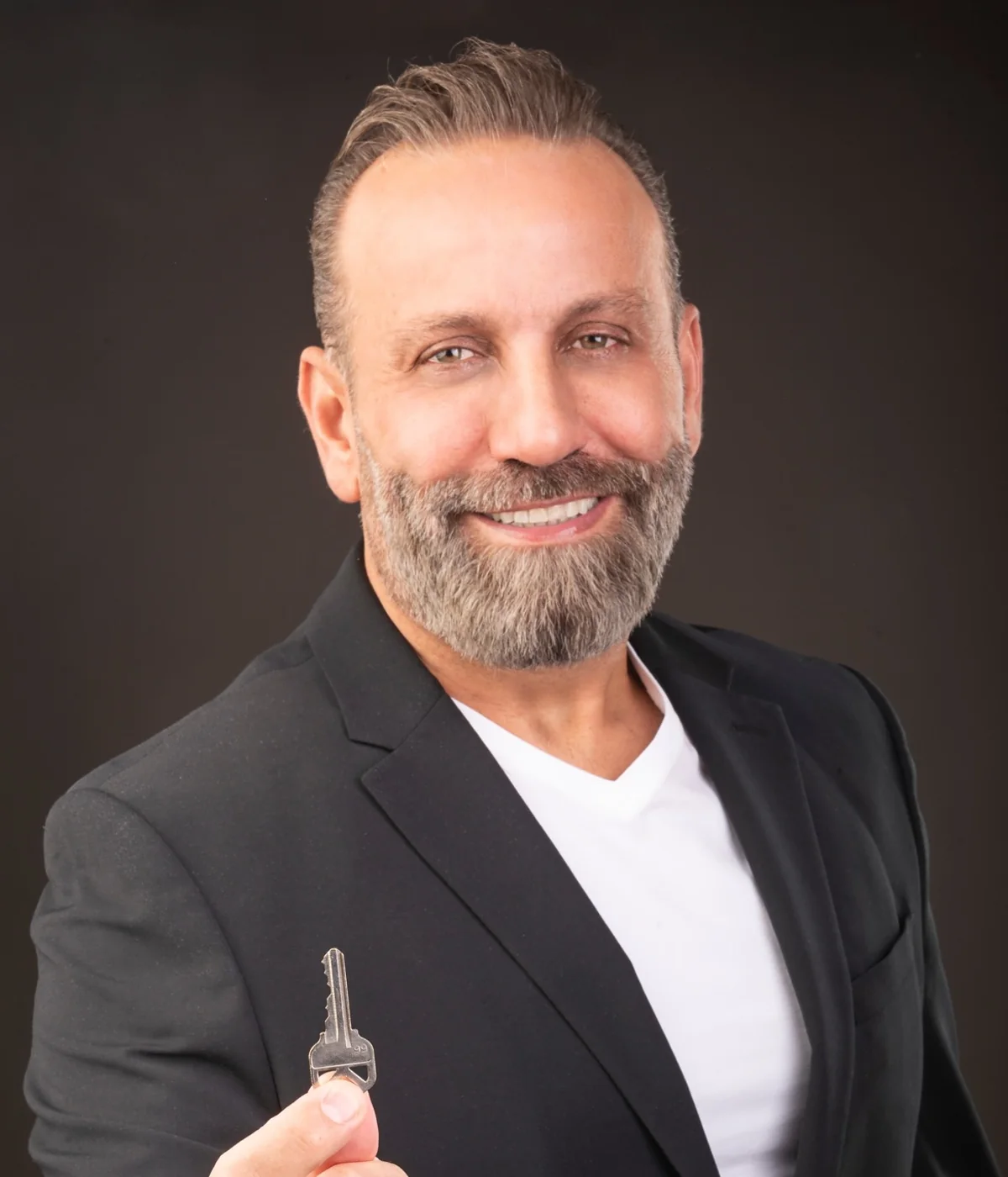 Adam Hage, founder and principal broker of Atlas Group, smiling and holding a house key